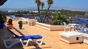 A rooftop terrace with lounge chairs, tables, and potted plants. - Golden Beach Appart'hotel (Agadir)