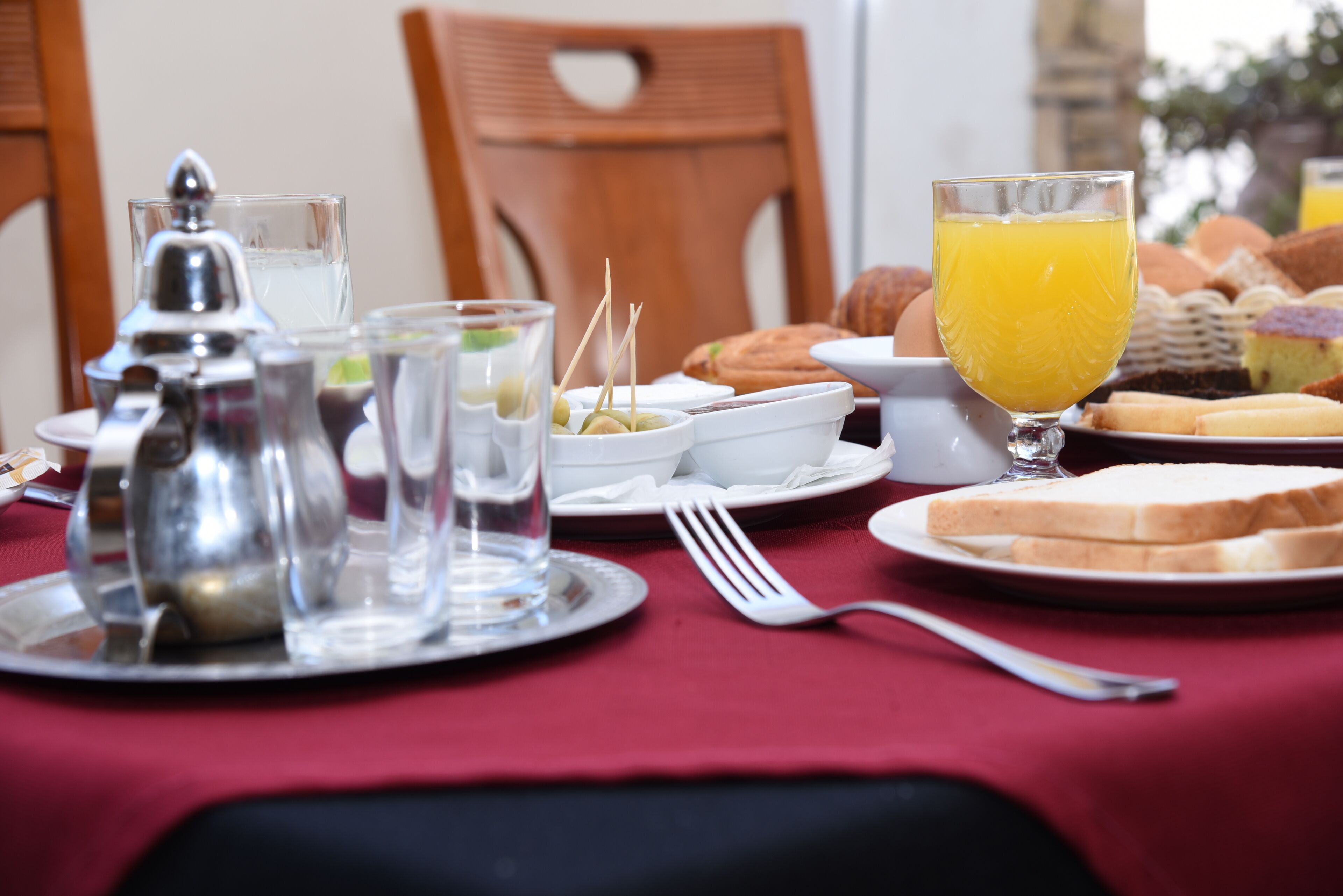 A breakfast setting with a table set for two, including plates with toast, a glass of orange juice, and various breakfast items.