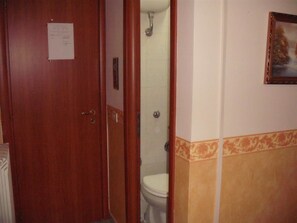 A bathroom with a wooden door, a white toilet, and a shower stall. - Hotel Alloggio Del Conte (Naples)