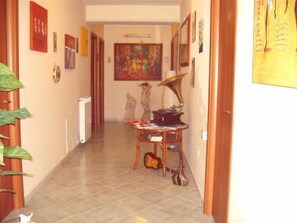 A hallway with a radiator, a table with a gramophone, and a guitar. - Hotel Alloggio Del Conte (Naples)