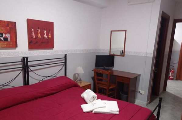 A hotel room with a bed, a desk, a chair, a television, and artwork on the wall. - Hotel Alloggio Del Conte (Naples)