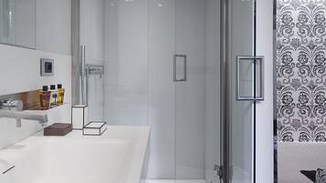 A modern bathroom with a glass-enclosed shower, a large white sink, and a mirror above it.