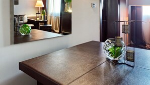 Une chambre d’hôtel moderne avec un grand miroir, un plafond en bois, une table de couleur marron foncé et un bol décoratif vert.