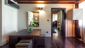 Un espace repas moderne avec une longue table, des bancs rembourrés, un miroir et un couloir menant à une autre pièce.