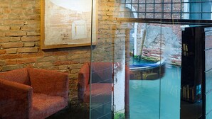 Un intérieur moderne avec un mur en verre, un fauteuil rouge et un tableau encadré accroché au mur.