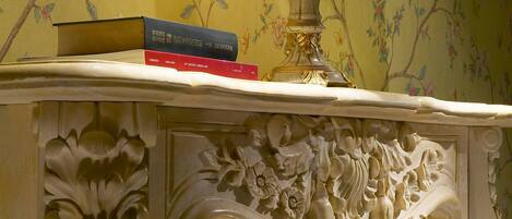 A marble fireplace with intricate floral carvings, a white lamp, and a book on top.