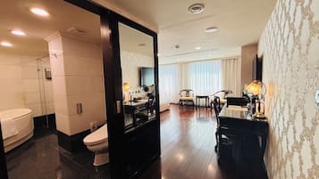 Quarto de hotel com banheiro, área de refeições e um espelho grande.