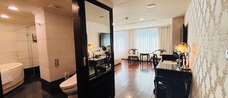 A hotel room with a bathroom, a dining area, and a large mirror.