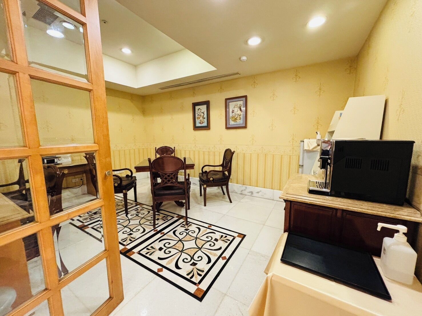 A hotel room with a dining area, a television, a coffee machine, and a bathroom.