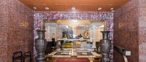 A lobby with a checkered floor, marble walls, and large vases.