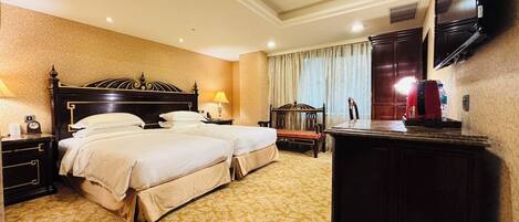 A hotel room with two beds, a desk, a chair, a television, and a minibar.