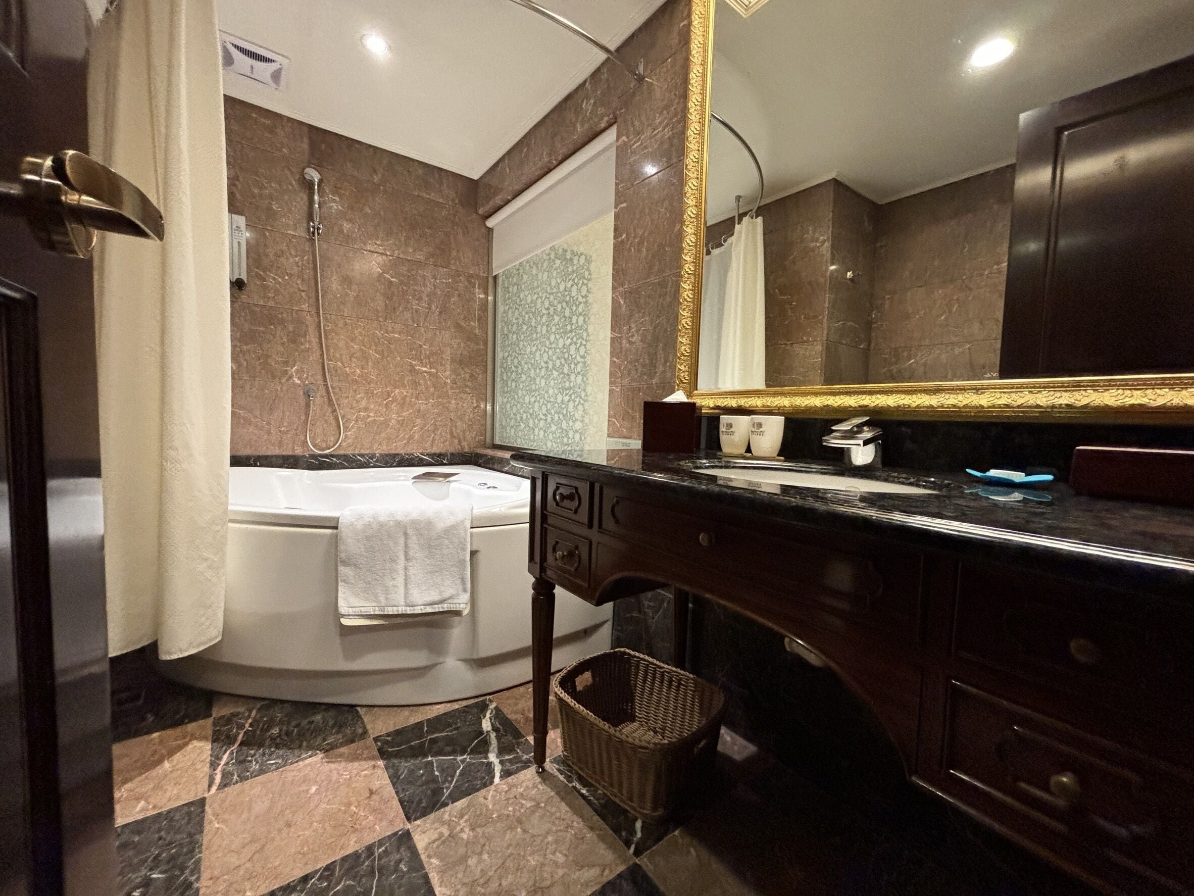 Un baño con bañera, un espejo grande, lavamanos y ducha.