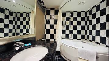 A bathroom with a checkered black and white tile wall, a white sink, and a bathtub with a towel.