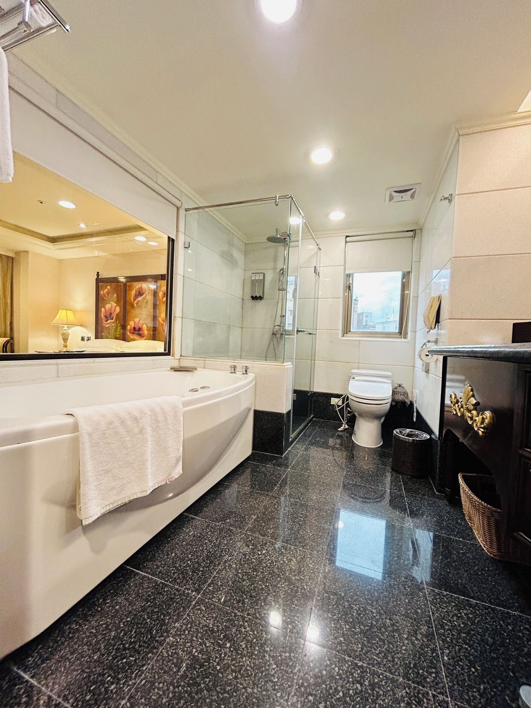 A modern bathroom with a large bathtub, a glass-enclosed shower, a toilet, and a vanity with a mirror.