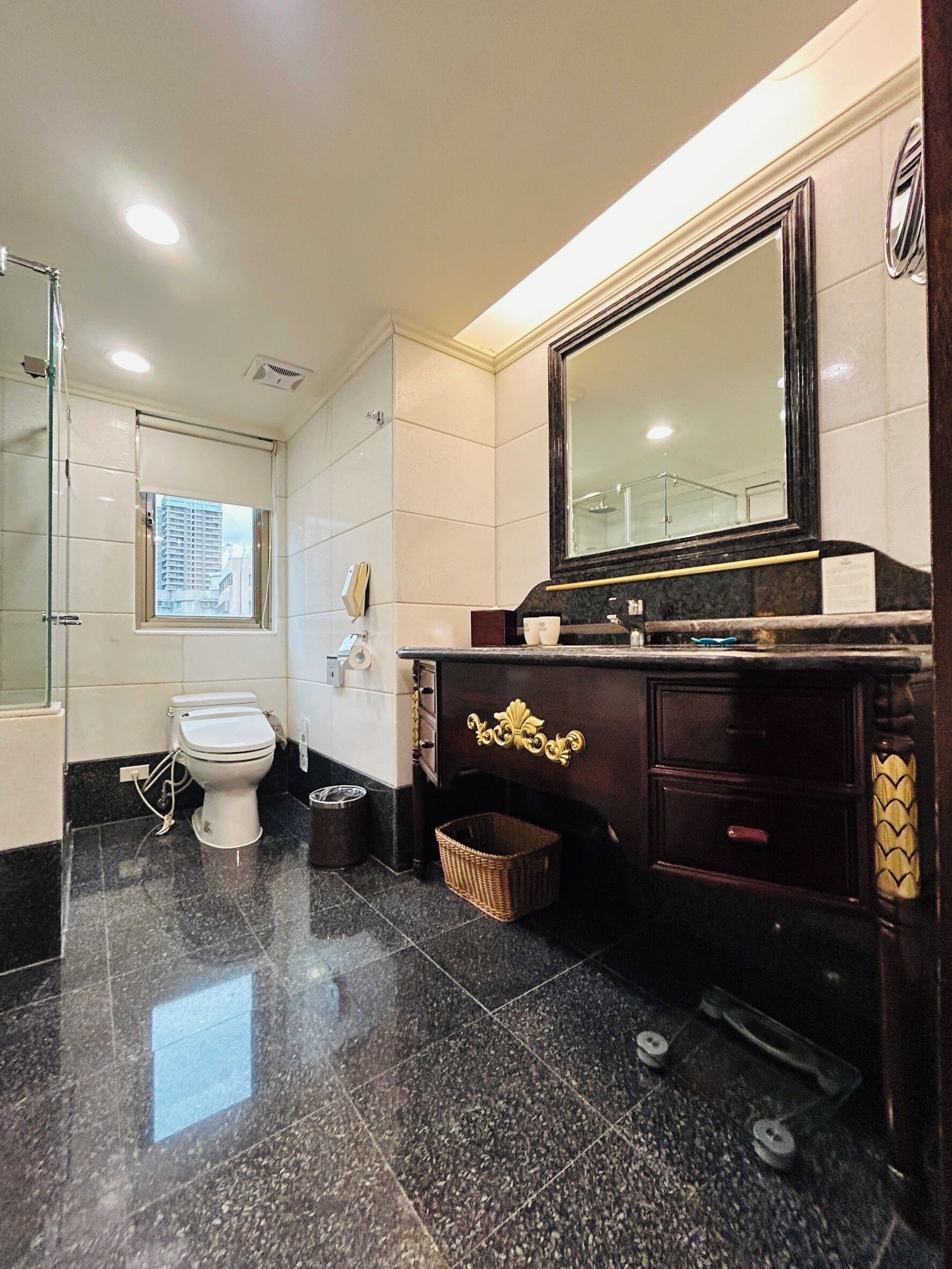 A bathroom with a toilet, a vanity with a mirror, and a shower area.