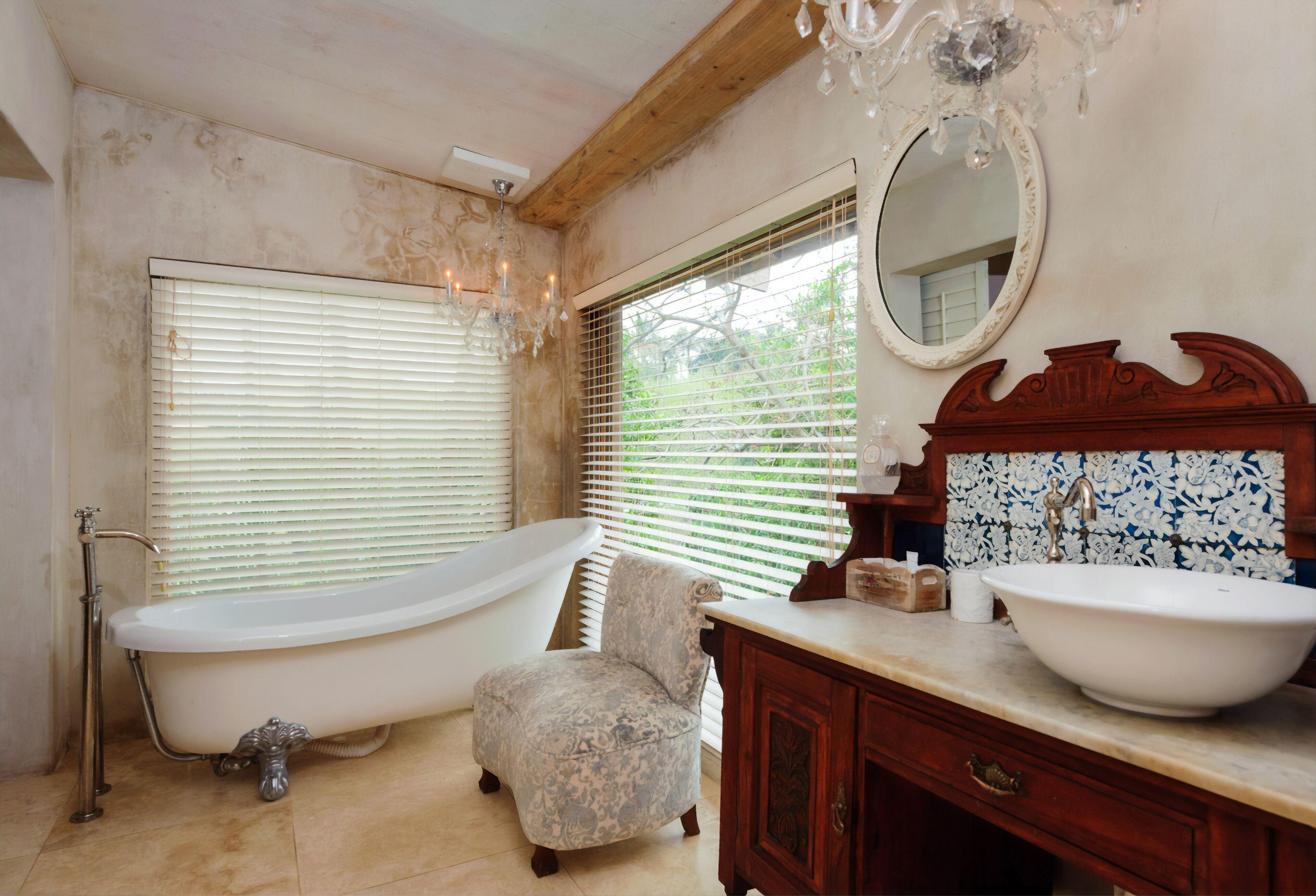 A bathroom with a freestanding bathtub, a vanity with a sink, a chair, and a large mirror.