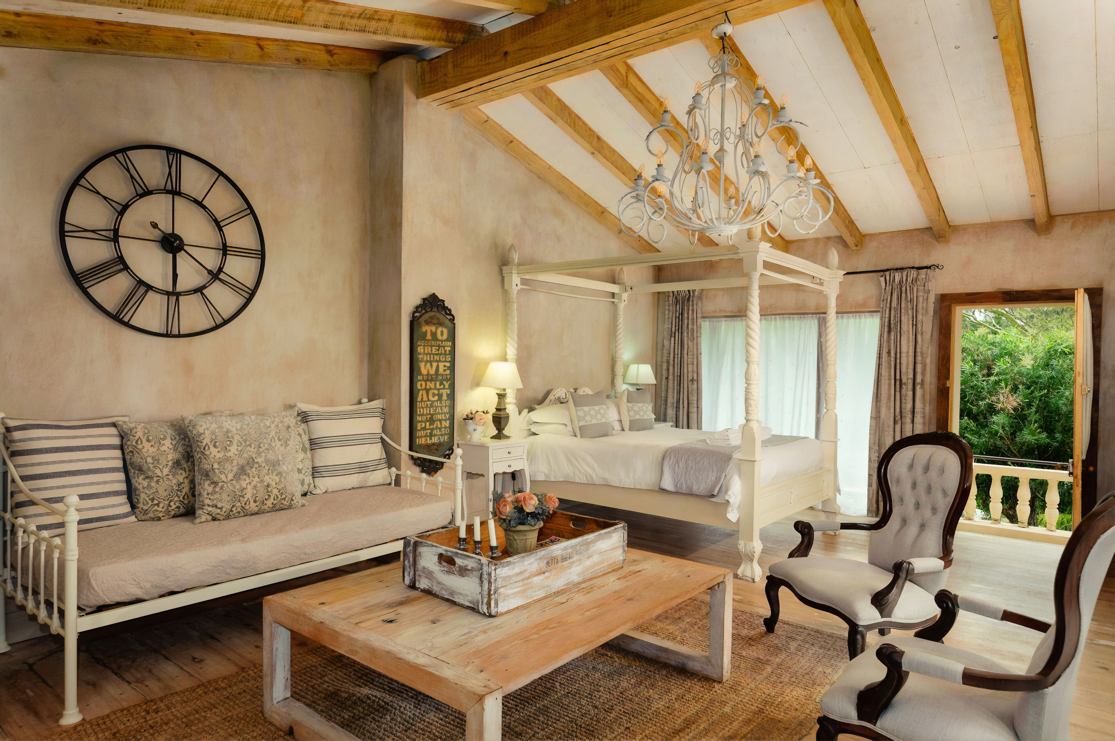 A cozy room with a four-poster bed, a wooden coffee table with candles, a sofa, and a chair.