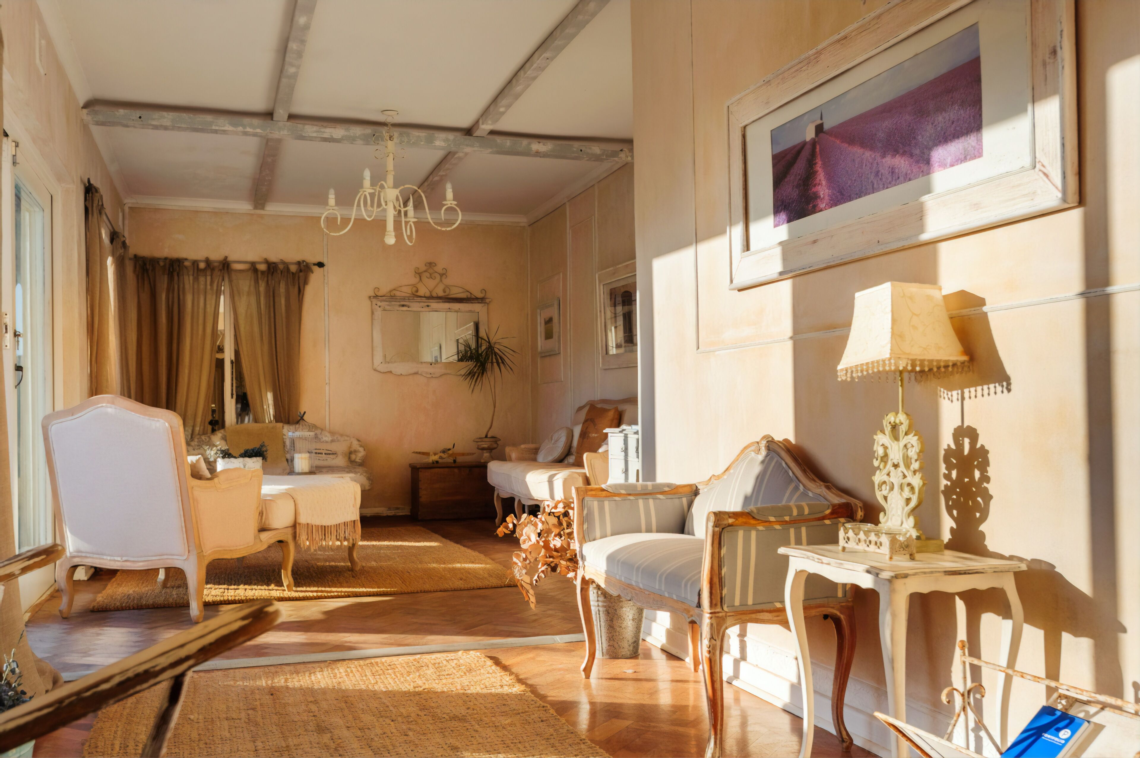 Una habitación con candelabro, cama, sillón, mesa y espejo.