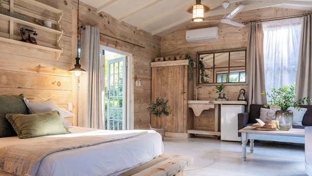 Ein schlichtes Schlafzimmer im Blockhausstil mit Bett, Nachttisch und Fenster.
