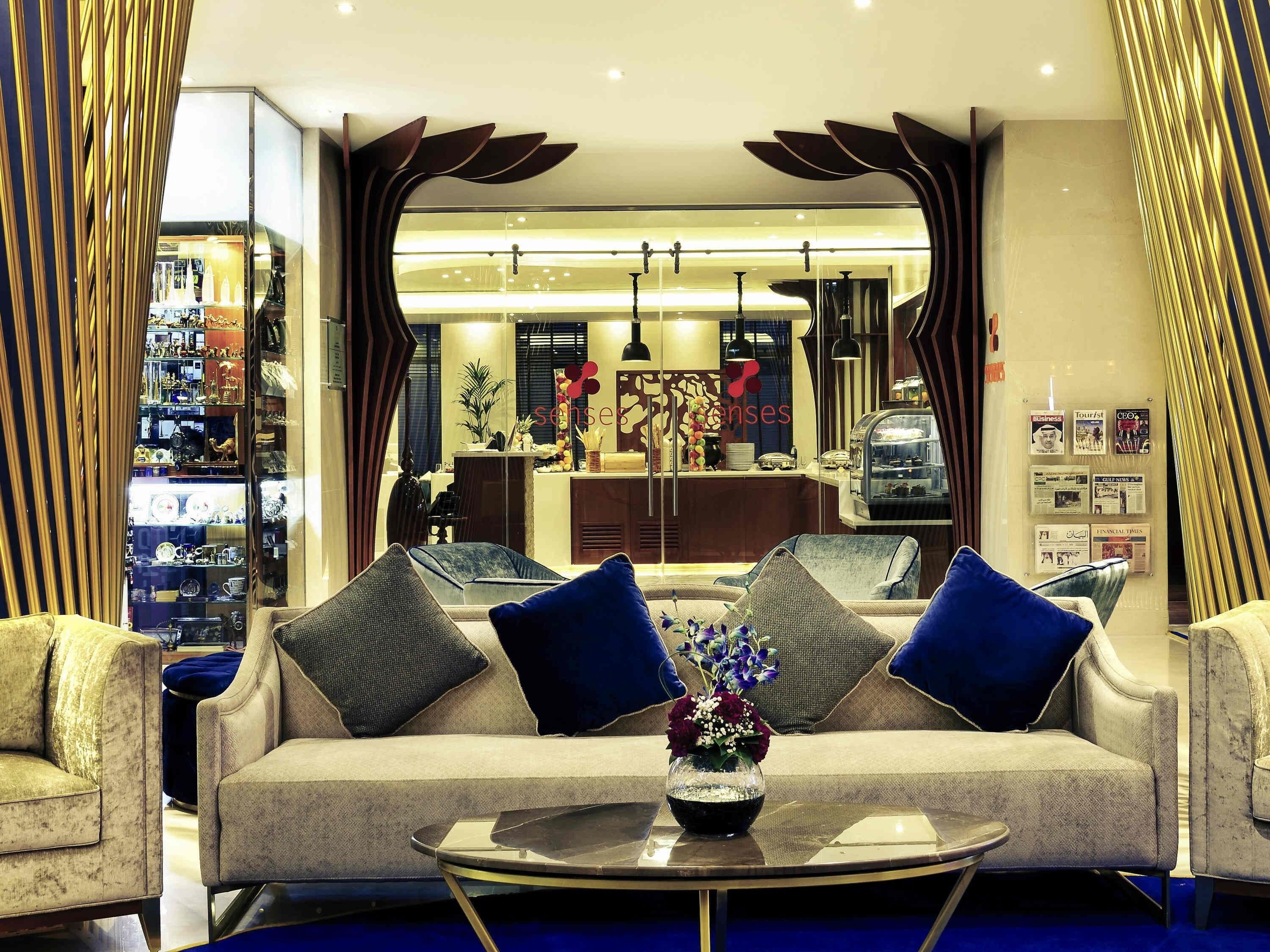 A hotel lobby with a sofa, chairs, a coffee table, and a reception desk.