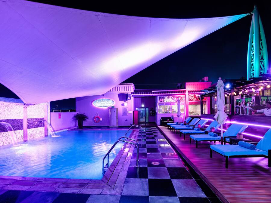Zona de piscina con sillones de descanso y un bar.