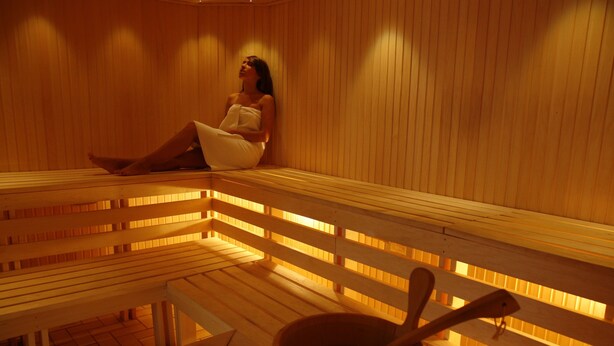Una sauna de madera con bancos y un cubo con una cuchara.
