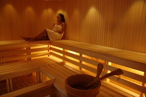 A wooden sauna with benches and a bucket with a ladle.