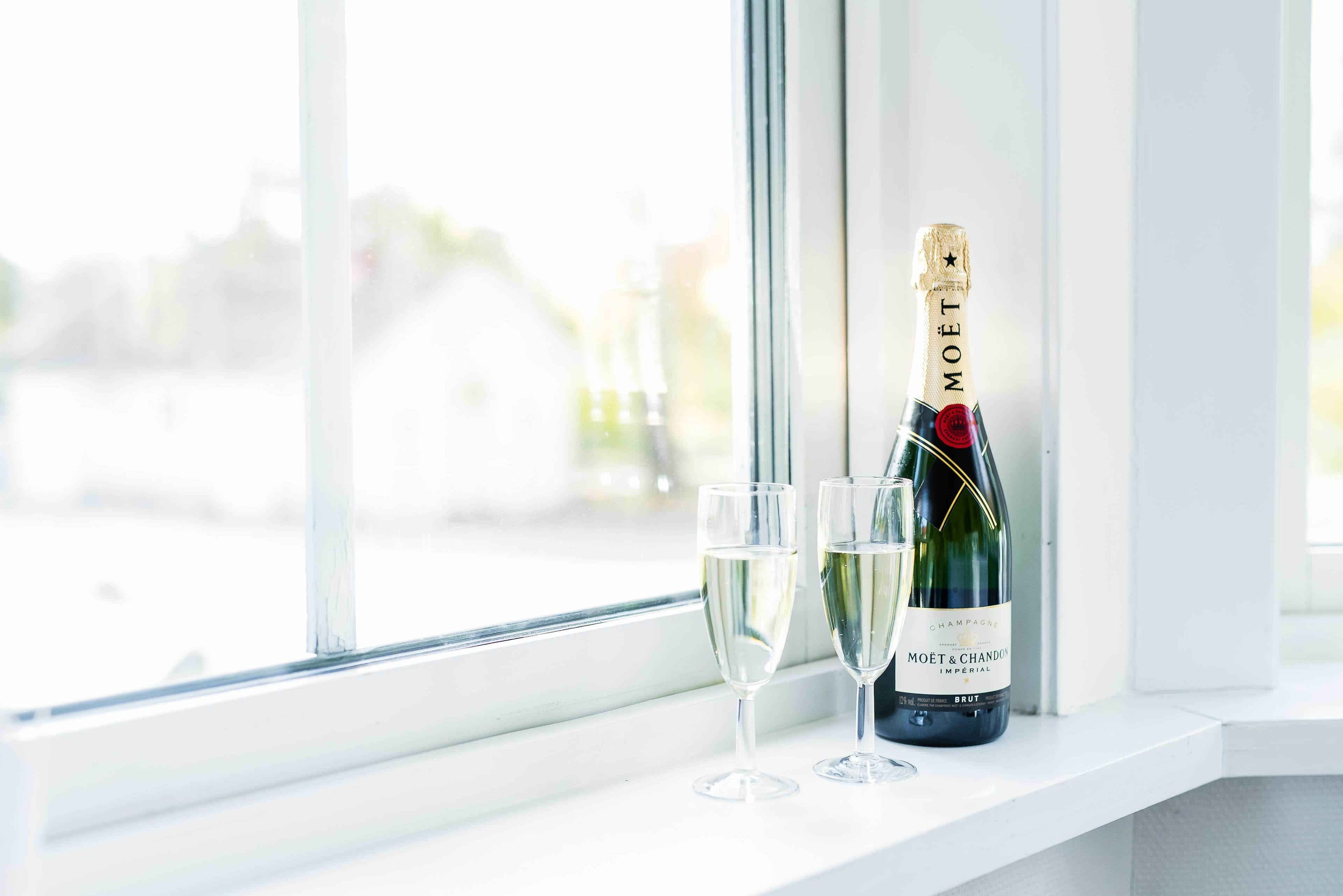 Una botella de champán Moët & Chandon y dos copas sobre un alféizar.