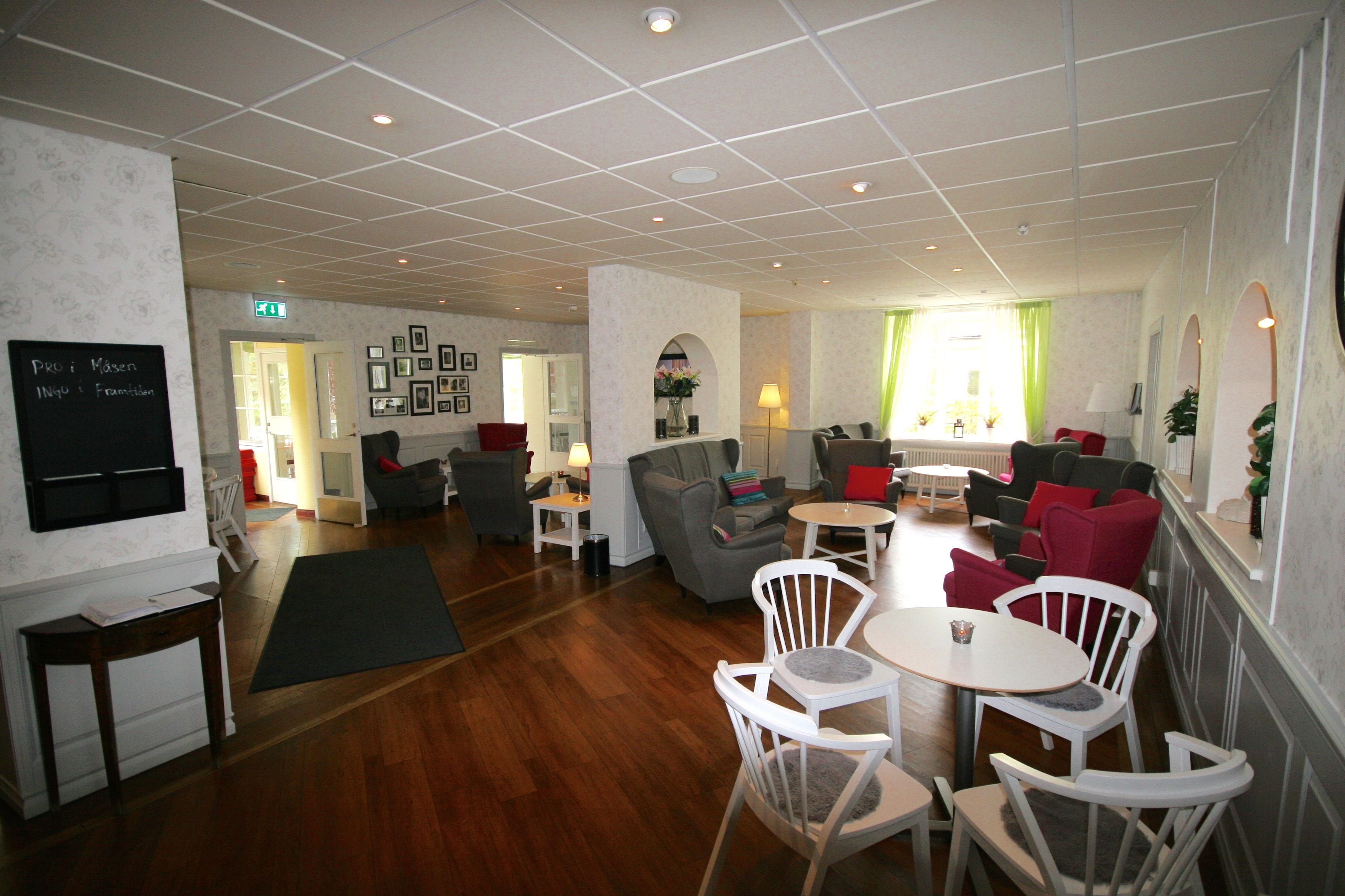A modern lounge area with a wooden floor, white furniture, and a flat-screen TV mounted on the wall.