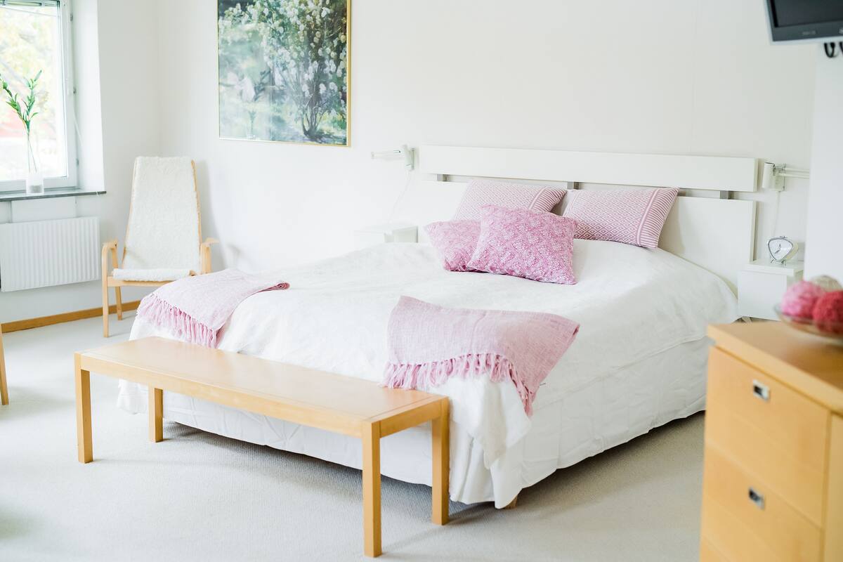 A neatly arranged bedroom with a bed, a bench, a chair, and a dresser.
