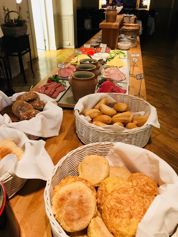 A buffet table with various food items including bread, pastries, and meats.