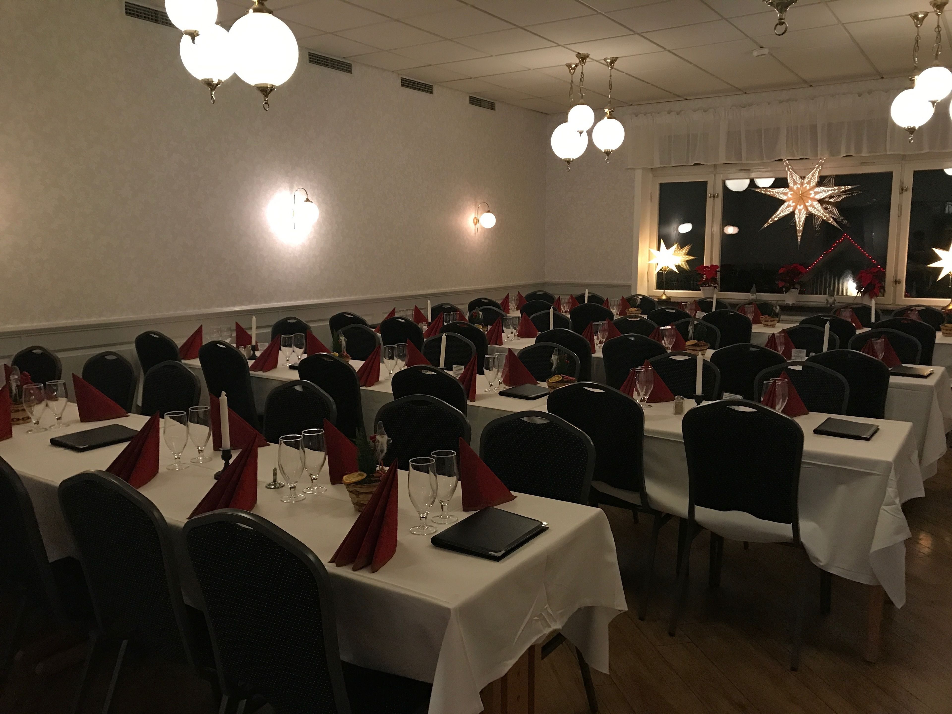A banquet hall with multiple tables set for dining, each with chairs, glasses, and napkins.