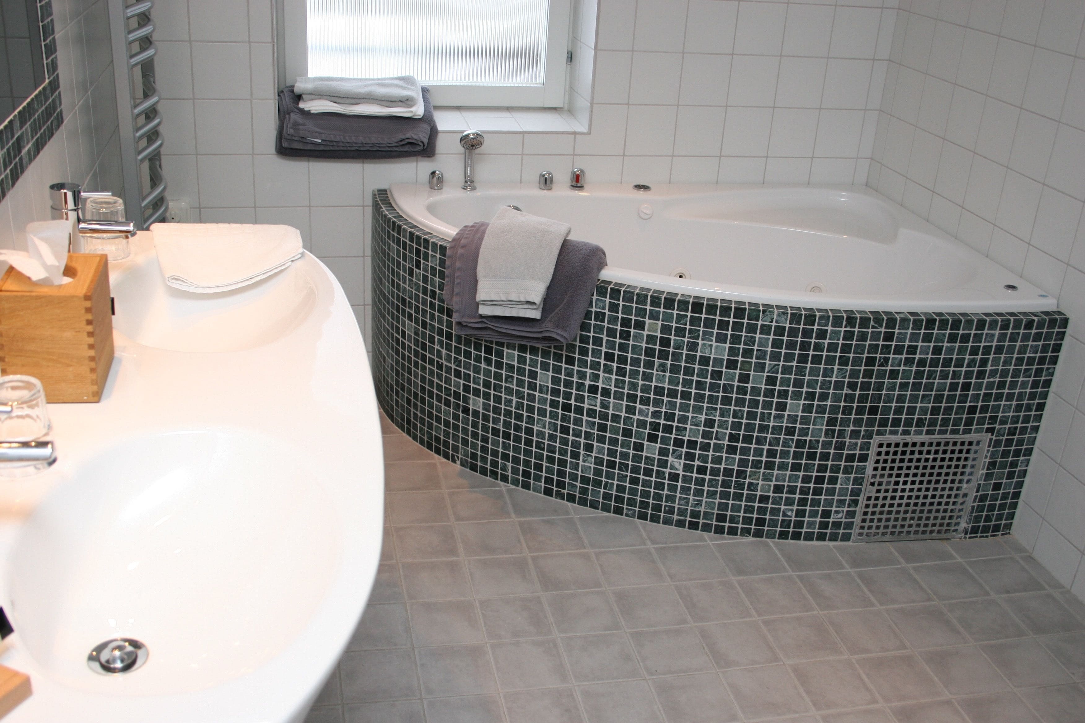 Un baño con una bañera independiente, un lavamanos y un ventanal.