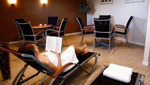 Un cuarto de spa con sillas de masaje, un rincón para leer y una pequeña mesa con una planta.