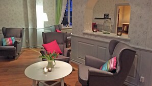 Una sala de estar con dos sillones, una mesa blanca y un florero con flores.