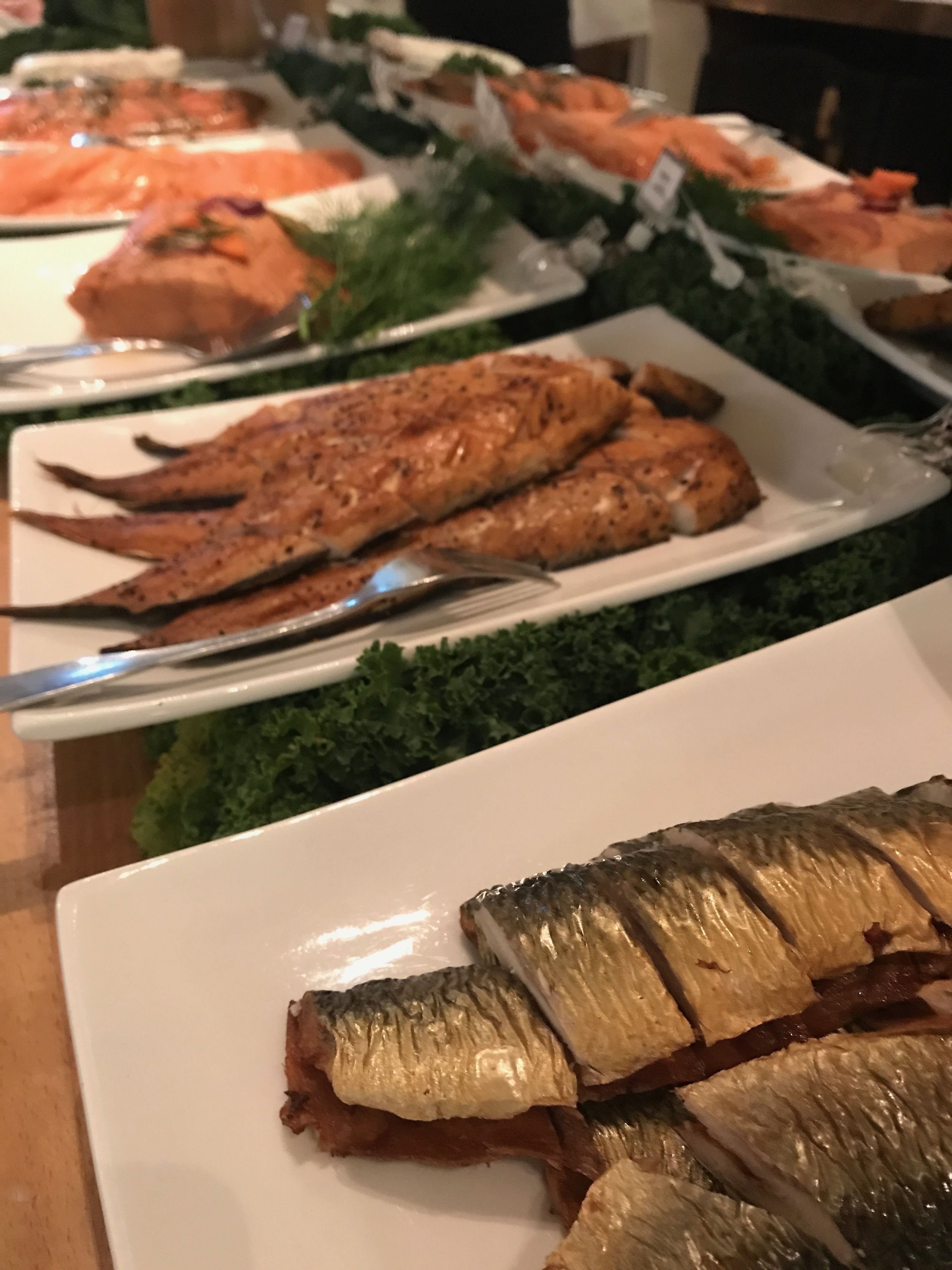 A buffet with various dishes including grilled fish and salads.