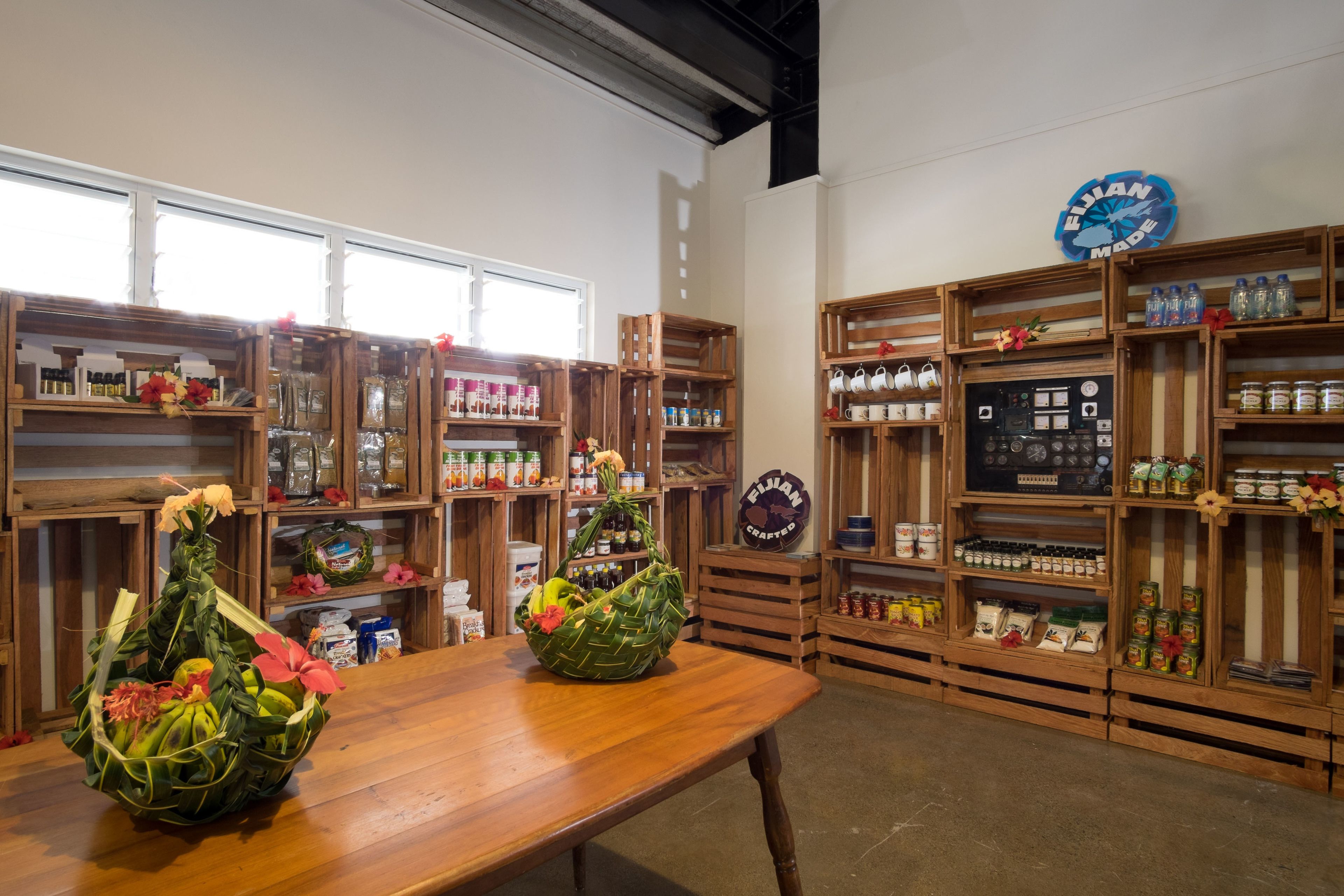 Un interior de madera con estantes llenos de diversos objetos, una mesa con cestas decorativas y un reloj de pared.