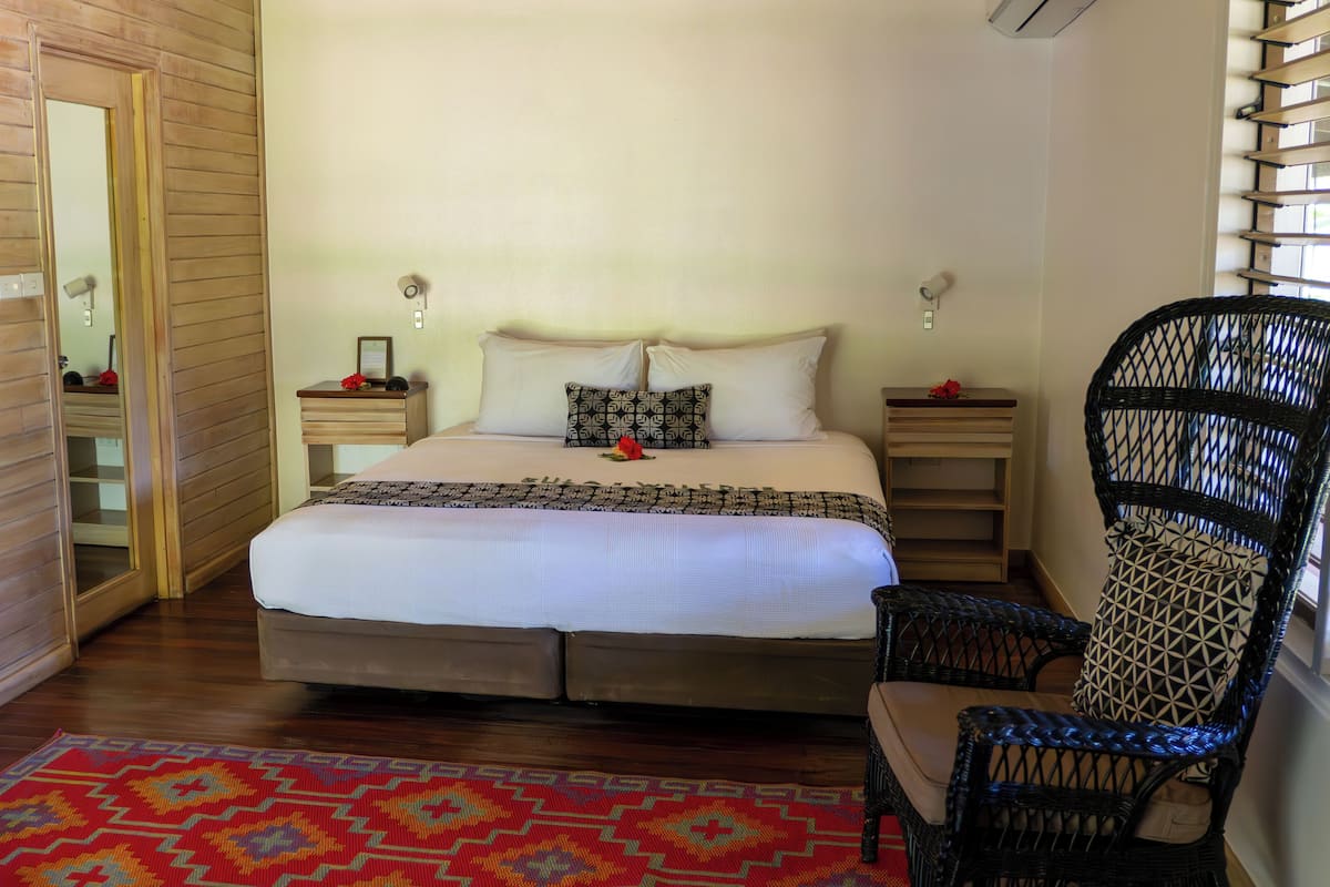 Une chambre à coucher avec un grand lit, deux tables de chevet, une chaise et un tapis à motifs.