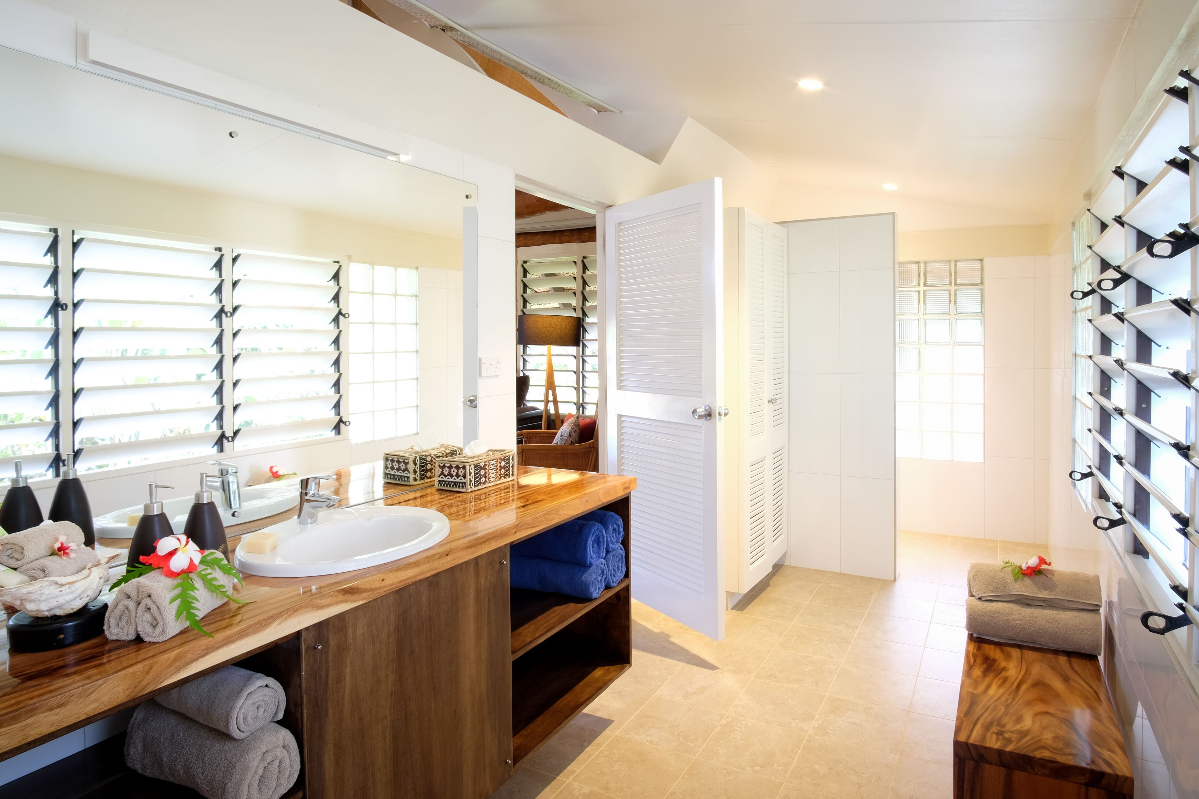 A modern bathroom with a wooden vanity, a large mirror, and a towel rack.