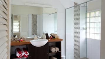 Un baño moderno con un espejo grande, lavamanos blanco y cabina de ducha de vidrio.