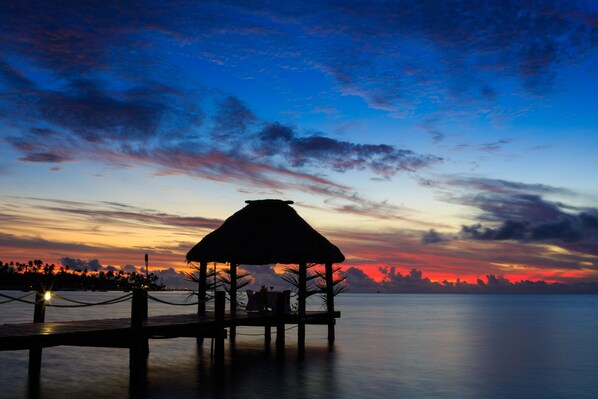 A thatched-roof structure on a pier with a view of the sunset over water. - Musket Cove Island Resort & Marina (Malolo Lailai Island)