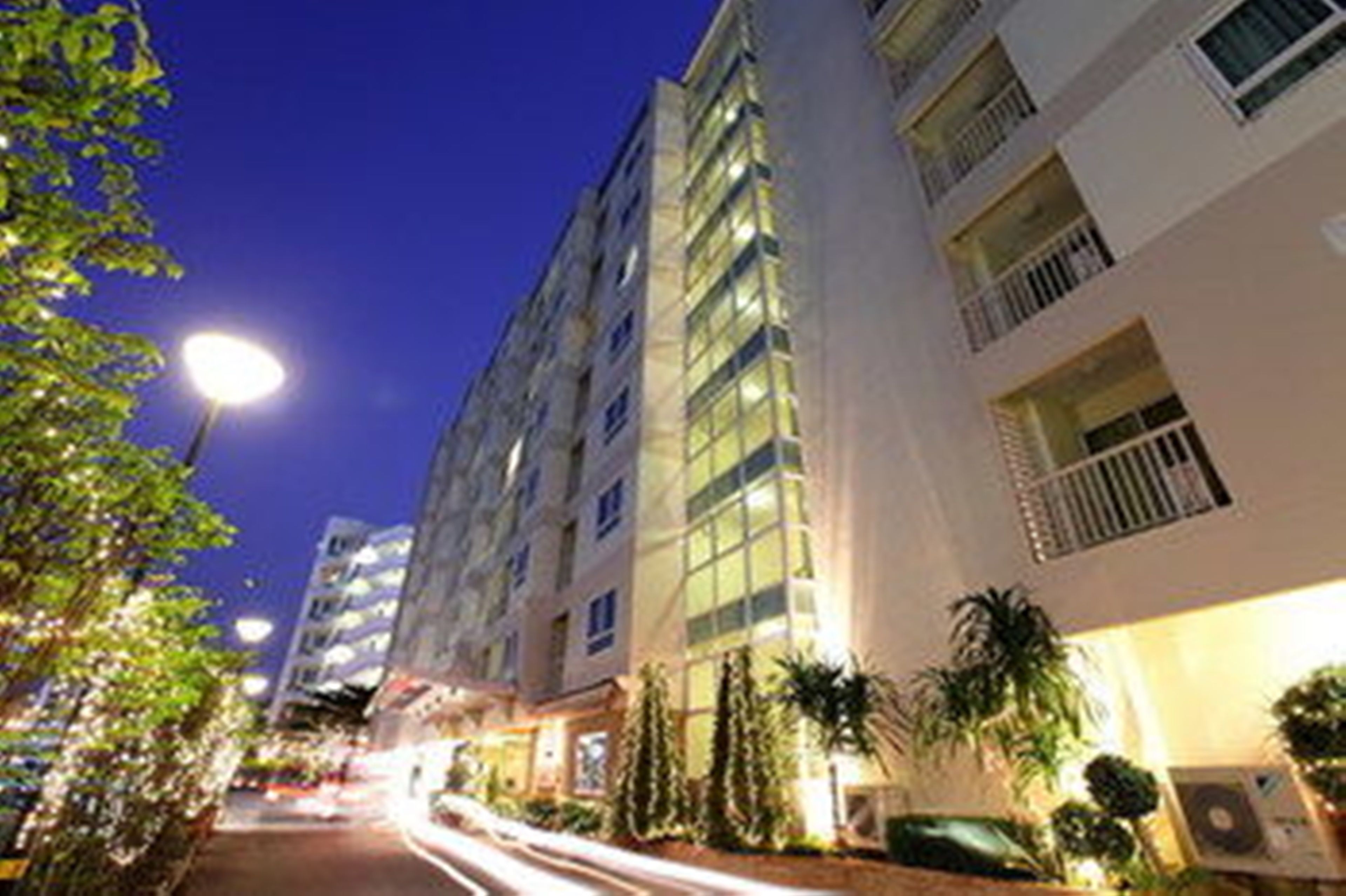 A multi-story hotel with a modern design, featuring balconies on each floor and a well-lit exterior.