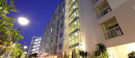 A multi-story hotel with a modern design, featuring balconies on each floor and a well-lit exterior.