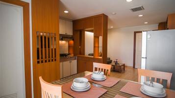 A modern kitchen with wooden cabinets, a dining table set with plates, and a small seating area.