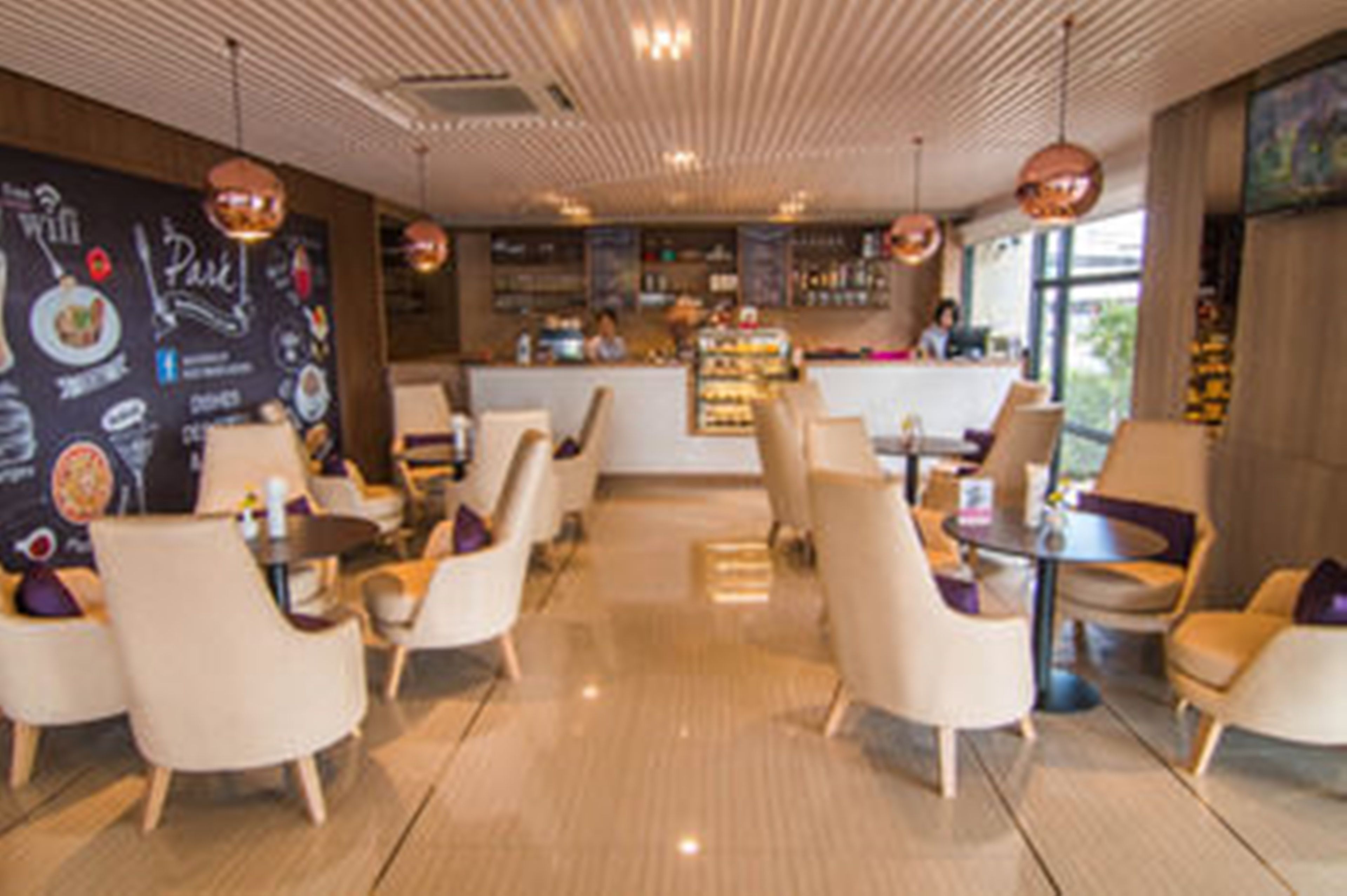A modern cafe with a bar area, seating arrangements, and a menu wall.