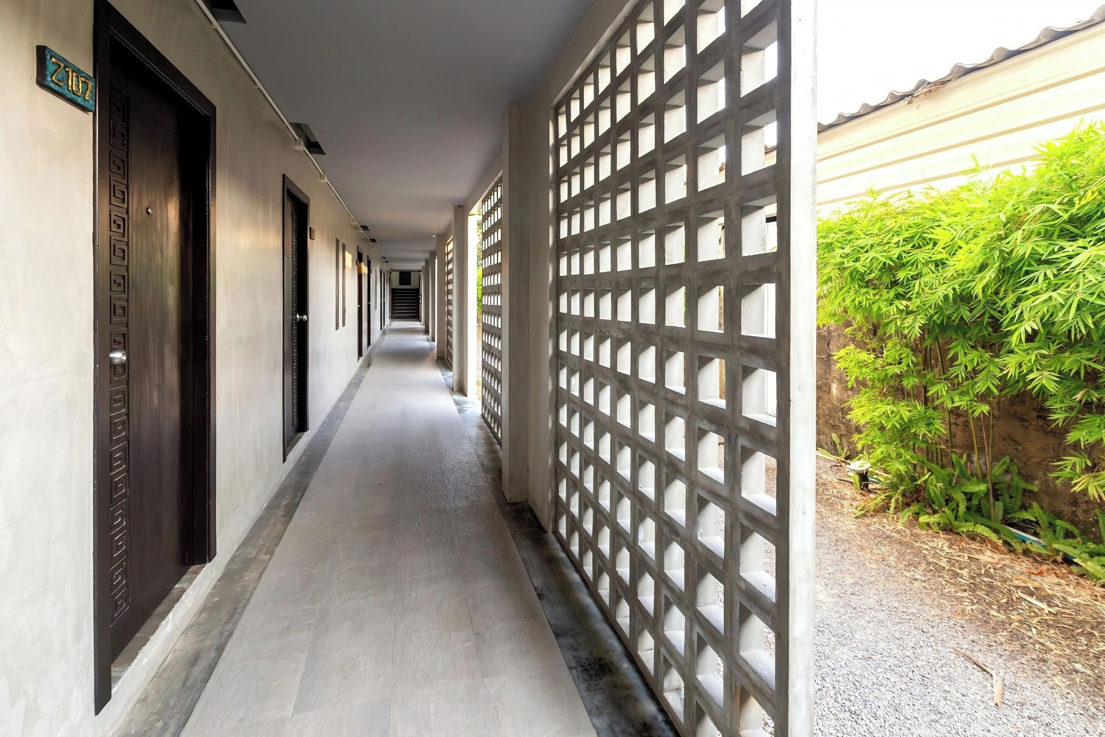 A corridor with doors on the left and a lattice fence on the right.