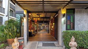 A corridor with a wooden floor leading to a room with a bed and a bench. - Phuketa Hotel Phuket Town (Ratsada)