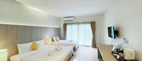 A hotel room with two beds, a desk with a coffee maker, a TV, and a window with curtains.