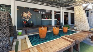 A modern outdoor pool area with wooden tables and large urns. - Phuketa Hotel Phuket Town (Ratsada)