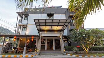 A modern hotel entrance with a covered entrance, stone pillars, and a sign reading "phu-ke-ta The Hip Service Apartment & Hotel".